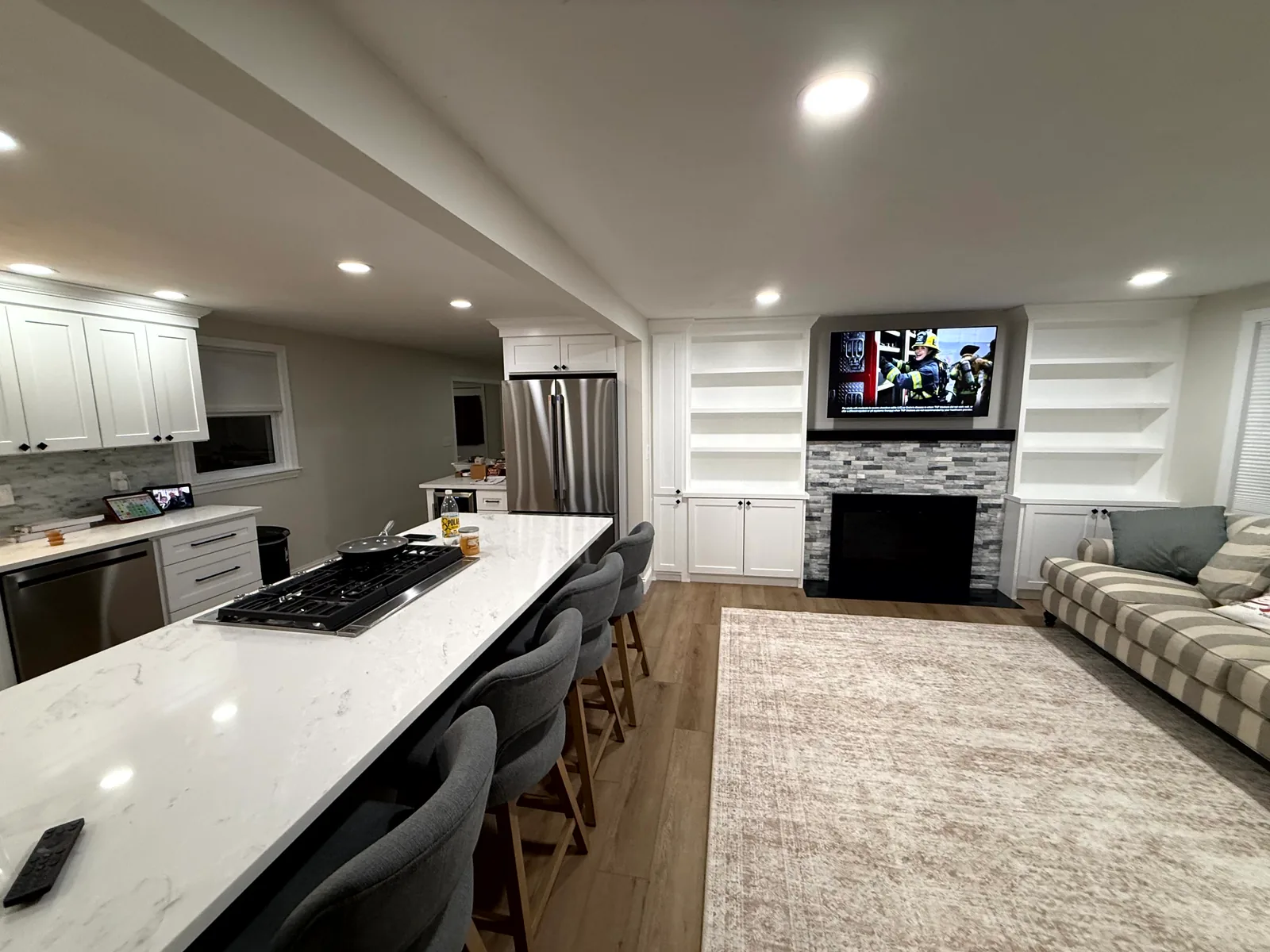 Recessed lighting installed across an open-concept kitchen counter and living area