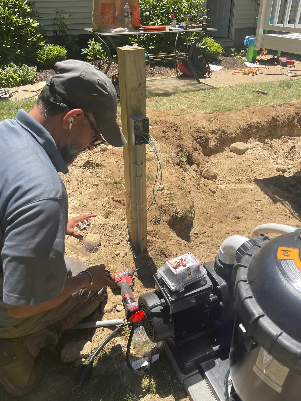 Electrician wiring pool pump equipment and a weatherproof box during an installation in progress