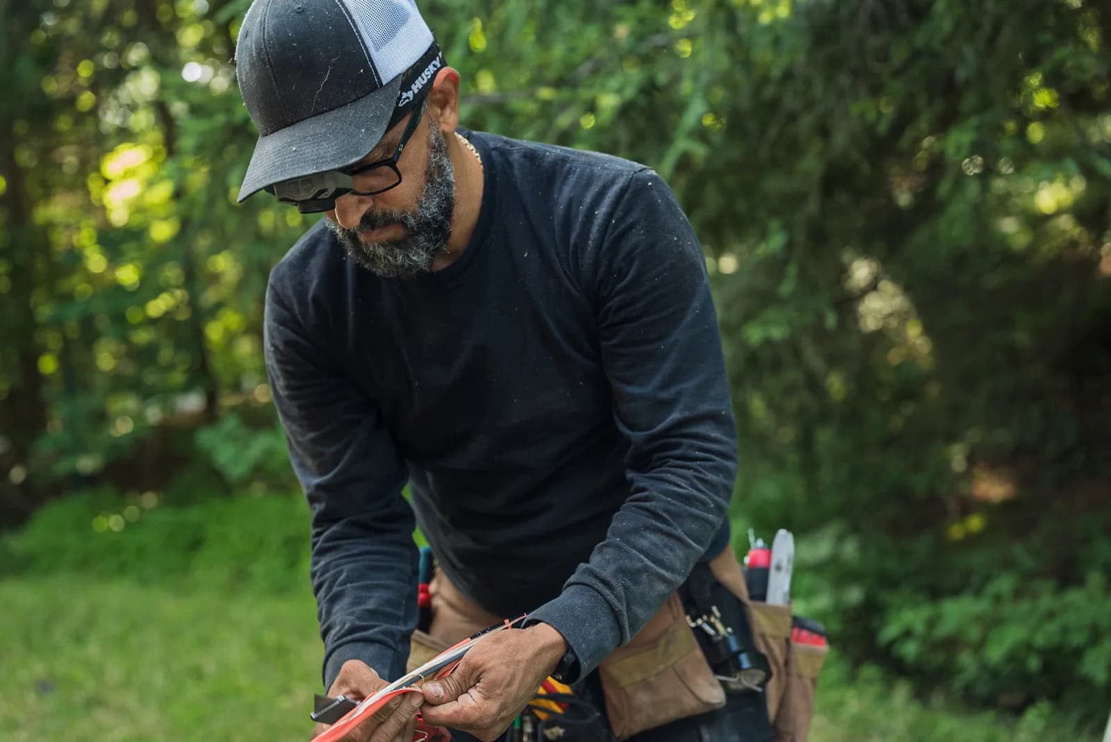 Electrician preparing wire at his tool belt outside a home
